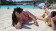 Two female friends sunbathing and chatting on the beach