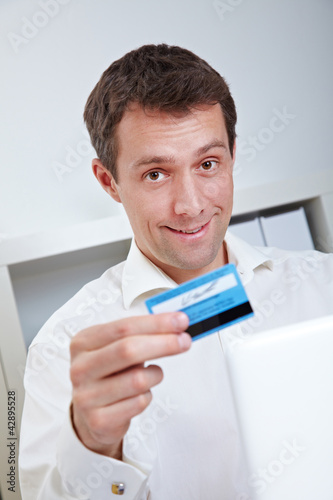 Photo: Mann mit Kreditkarte vor Laptop Mann mit Kreditkarte vor Laptop