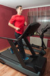 Young handsome man running on treadmill in gym