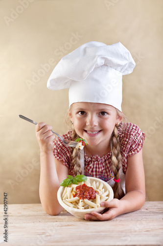 Foto: Little chef eating pasta with tomato sauce and basil Little chef eating pasta with tomato sauce and basil
