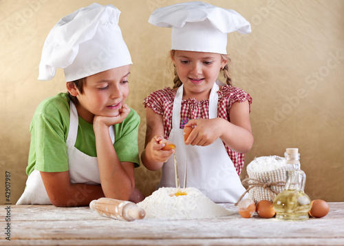 Foto: Kids preparing a cake - starting with flour and eggs Kids preparing a cake - starting with flour and eggs