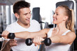 Trainer helping a woman work out with dumbbells