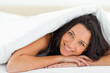 Woman with green eyes under the duvet