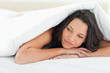 Cute young woman under the duvet