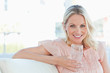 Blonde woman smiling at the camera while holding a glass