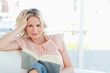 Smiling female lying on a sofa while reading a book