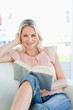 Smiling woman lying on a sofa while reading a book