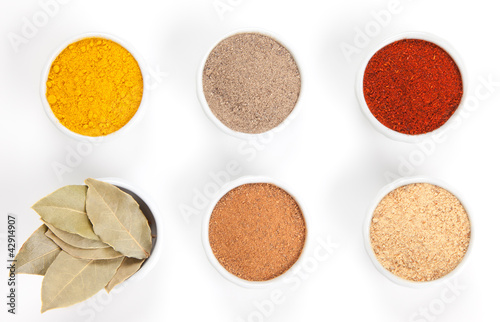 Photo: Different spices in white bowls isolated on white background. Different spices in white bowls isolated on white background.