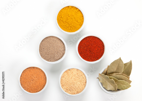 Photo: Different spices in white bowls isolated on white background. Different spices in white bowls isolated on white background.