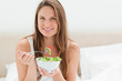Young woman smiling while eating a salad