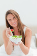 Close-up of a woman with a bowl of salad offering a tomato to eat