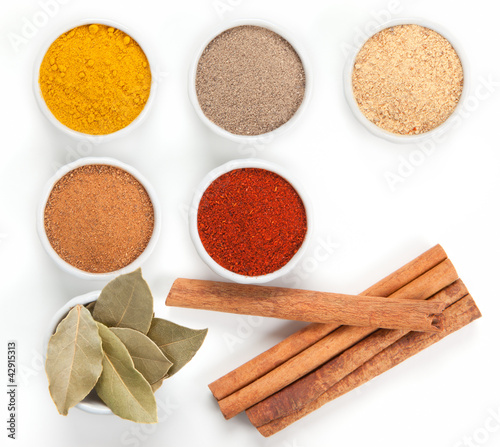 Photo: Different spices in white bowls isolated on white background. Different spices in white bowls isolated on white background.