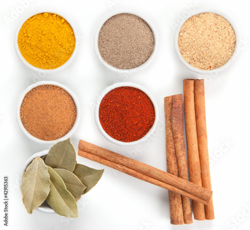 Photo: Different spices in white bowls isolated on white background. Different spices in white bowls isolated on white background.