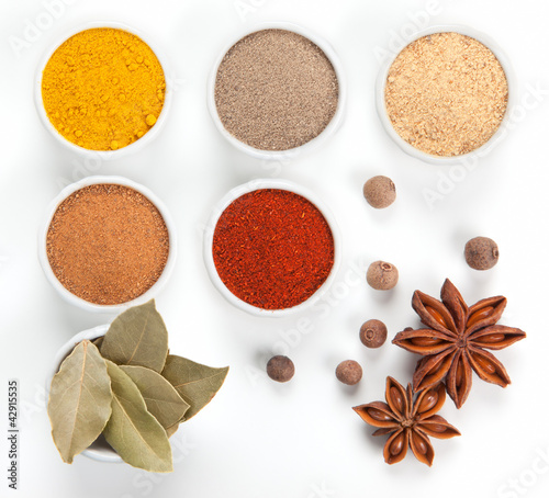 Photo: Different spices in white bowls isolated on white background. Different spices in white bowls isolated on white background.