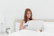 Redheaded sitting on her bed while using her credit card online