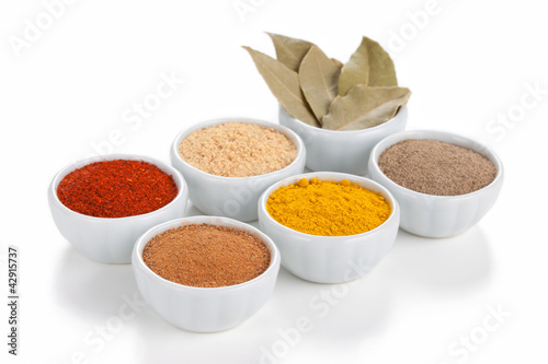 Photo: Different spices in white bowls isolated on white background. Different spices in white bowls isolated on white background.