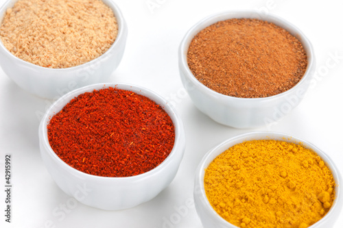 Photo: Different spices in white bowls isolated on white background. Different spices in white bowls isolated on white background.