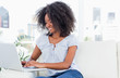 Fuzzy hair woman tapping on her laptop