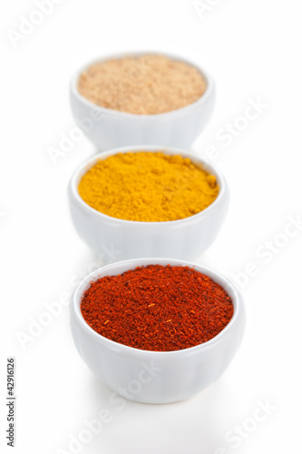 Photo: Different spices in white bowls isolated on white background. Different spices in white bowls isolated on white background.