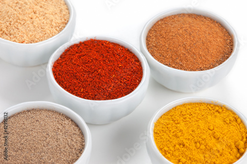 Photo: Different spices in white bowls isolated on white background. Different spices in white bowls isolated on white background.