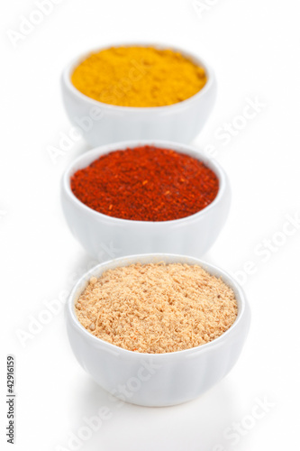 Photo: Different spices in white bowls isolated on white background. Different spices in white bowls isolated on white background.