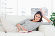 Portrait of a brunette reading on her sofa 