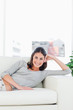 Portrait of a smiling brunette on her sofa 