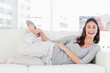 Portrait of a laughing brunette stretching on her sofa 
