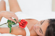 Brunette lying on her back with a rose