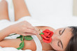 Brunette lying on her back while smelling a rose