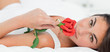 Portrait of a brunette lying on her back while smelling a rose