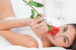 Portrait of a woman lying on her back while smelling a rose