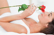 Woman lying on her back while smelling a rose