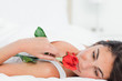 Beauty lying on her back while smelling a rose