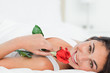 Portrait of a beauty lying on her back while holding a rose