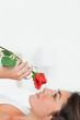 Close-up of a brunette lying on her back while smelling a rose
