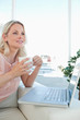 Smiling blonde on a laptop with a coffee
