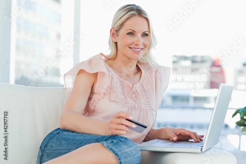 Photo: Smiling blonde buying online with a laptop Smiling blonde buying online with a laptop