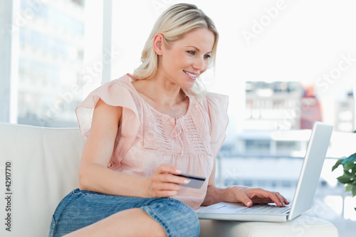 Photo: Happy blonde buying online with a laptop Happy blonde buying online with a laptop