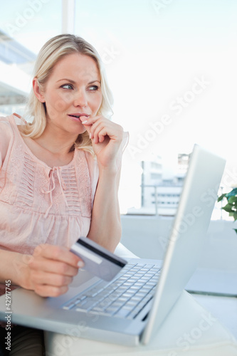 Photo: Close-up of a blonde thinking to shop online Close-up of a blonde thinking to shop online