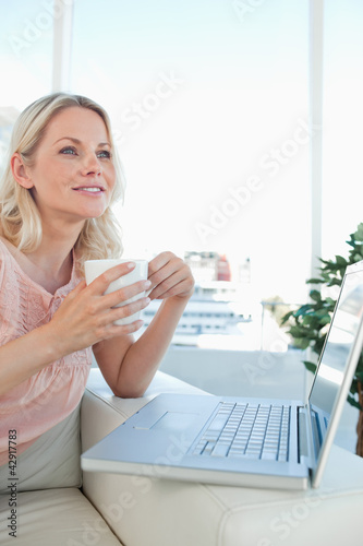 Photo: Smiling blonde on a laptop with a coffee Smiling blonde on a laptop with a coffee