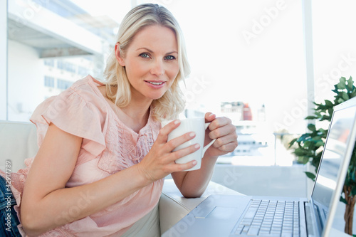 Photo: Portrait of a blonde on a laptop with a coffee Portrait of a blonde on a laptop with a coffee