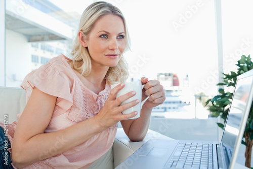 Photo: Blonde on a laptop with a hot chocolate Blonde on a laptop with a hot chocolate