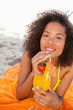 Young smiling woman holding an orange cocktail while looking at the camera
