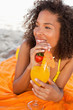 Young smiling woman looking towards the side while holding a fruit cocktail