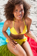 Young smiling woman looking at the camera while applying sunscreen on her body