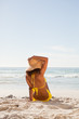 Photo: Rear view of an attractive woman holding her hat while looking at the ocean Rear view of an attractive woman holding her hat while looking at the ocean
