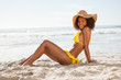Photo: Side view of a young smiling woman sitting in front of the ocean Side view of a young smiling woman sitting in front of the ocean