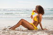 Photo: Young smiling woman drinking a fruit cocktail while sitting in front of the ocean Young smiling woman drinking a fruit cocktail while sitting in front of the ocean