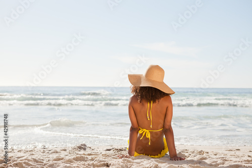 Photo: Young attractive woman looking at the ocean while sunbathing Young attractive woman looking at the ocean while sunbathing